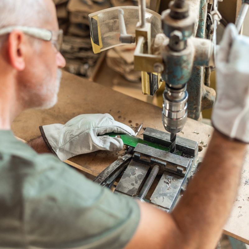 Adult person drilling metal with safety gloves